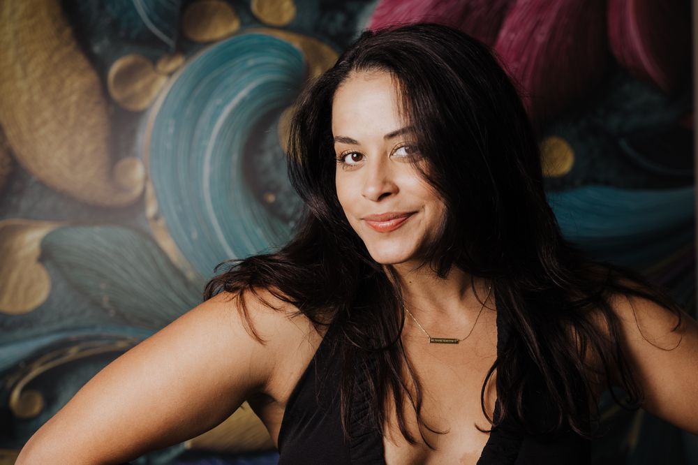 Mel smiling in front of a colorful mural
